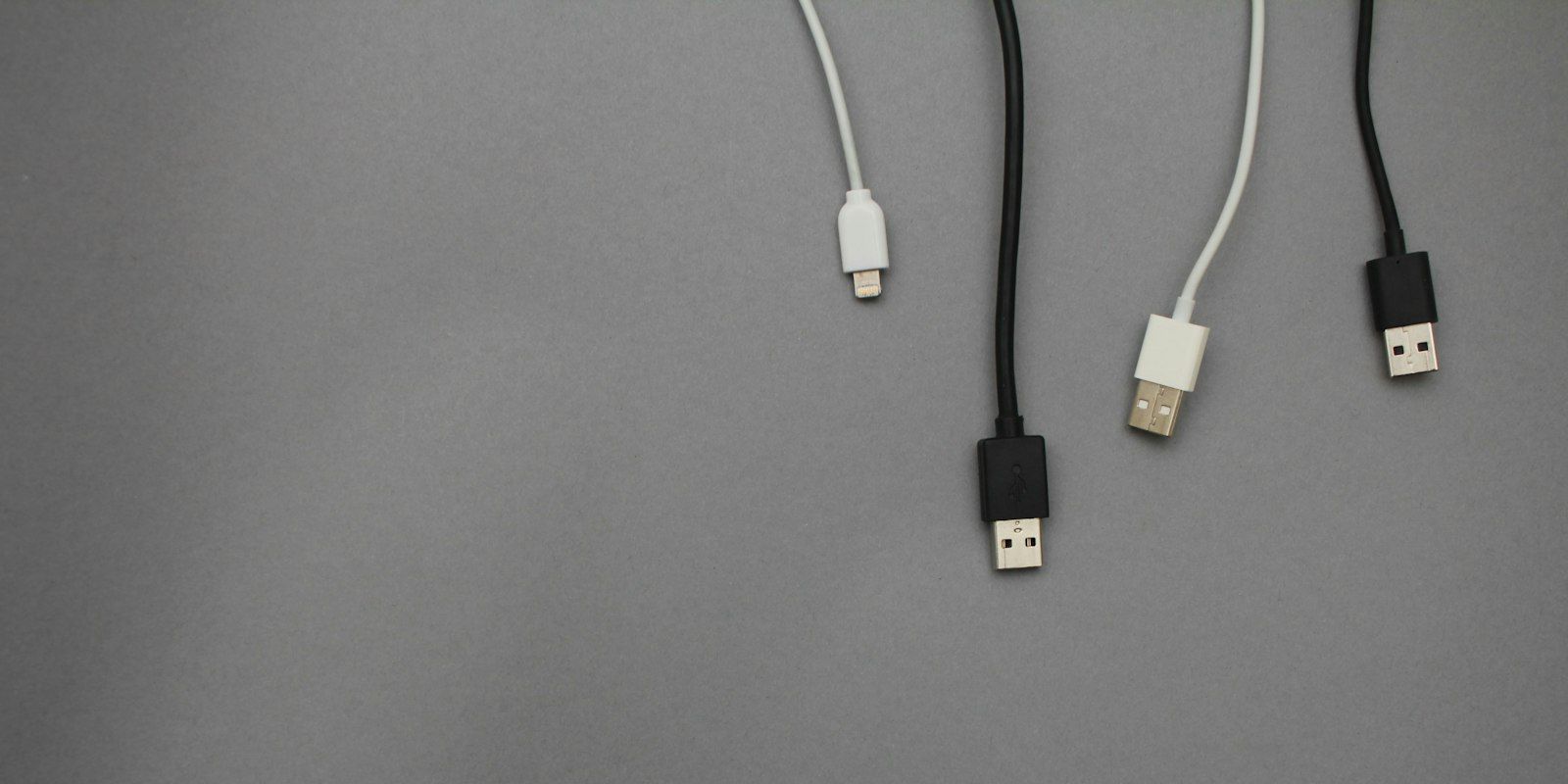 Black and white USB cables hanging over a grey background.